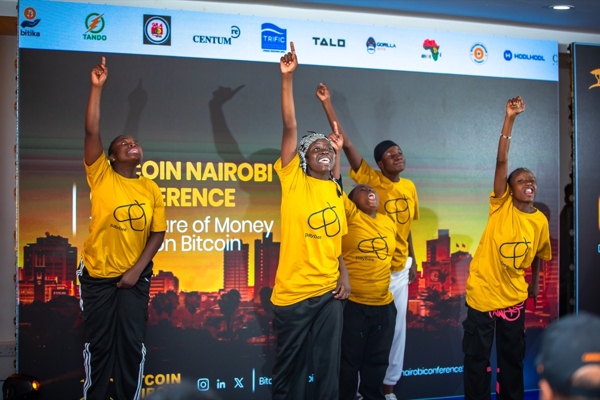 Youth performing on stage against the sponsor wall